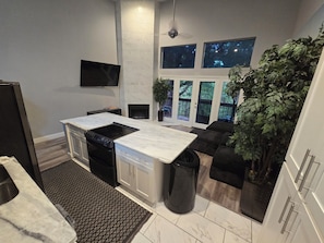Une cuisine moderne dotée d’une cuisinière intégrée, d’un grand îlot central et d’un coin salon offrant une vue sur l’extérieur.