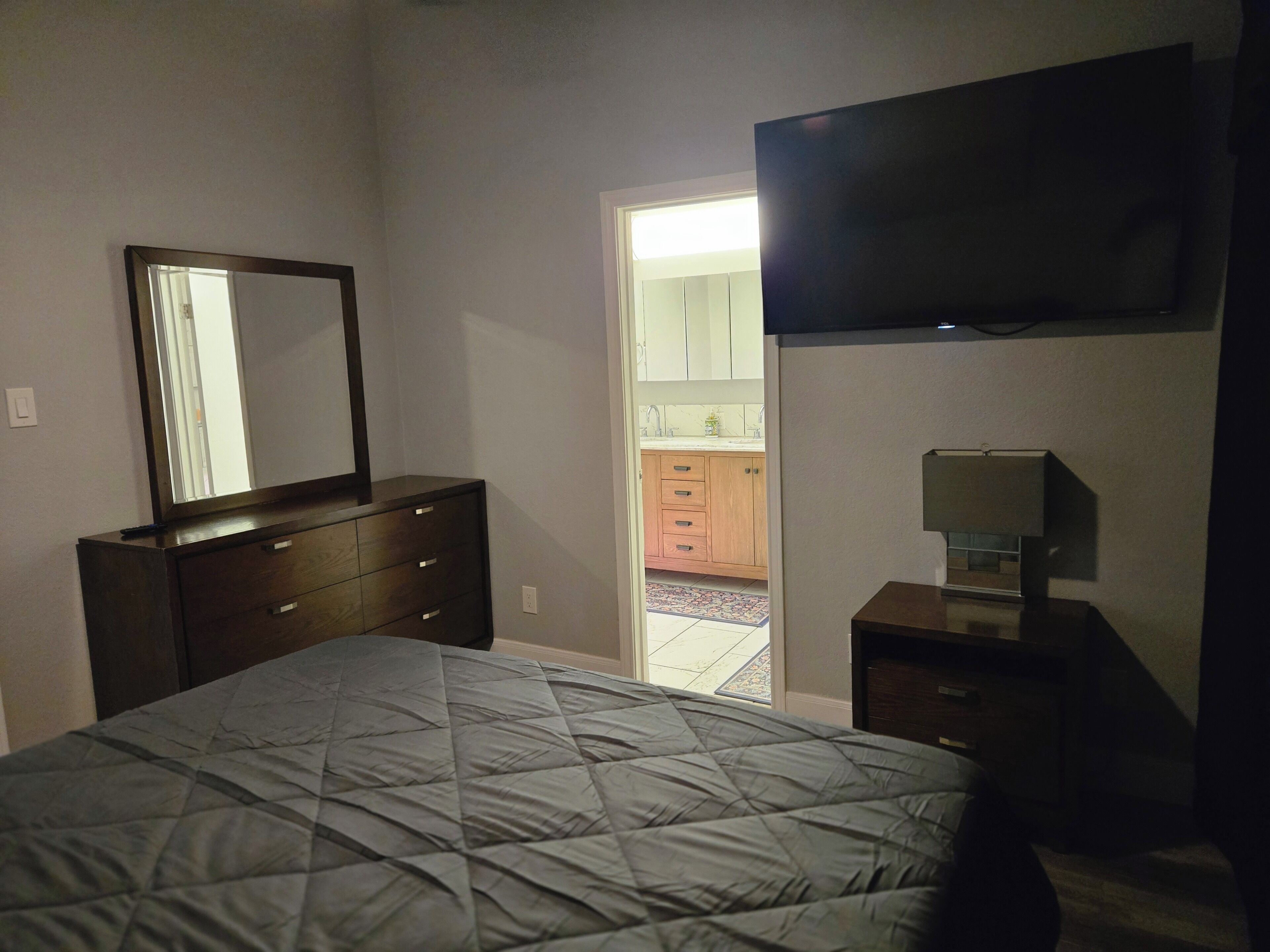 Ein Schlafzimmer mit einem Bett, einem Schminktisch, einem Spiegel und einem Fernseher.