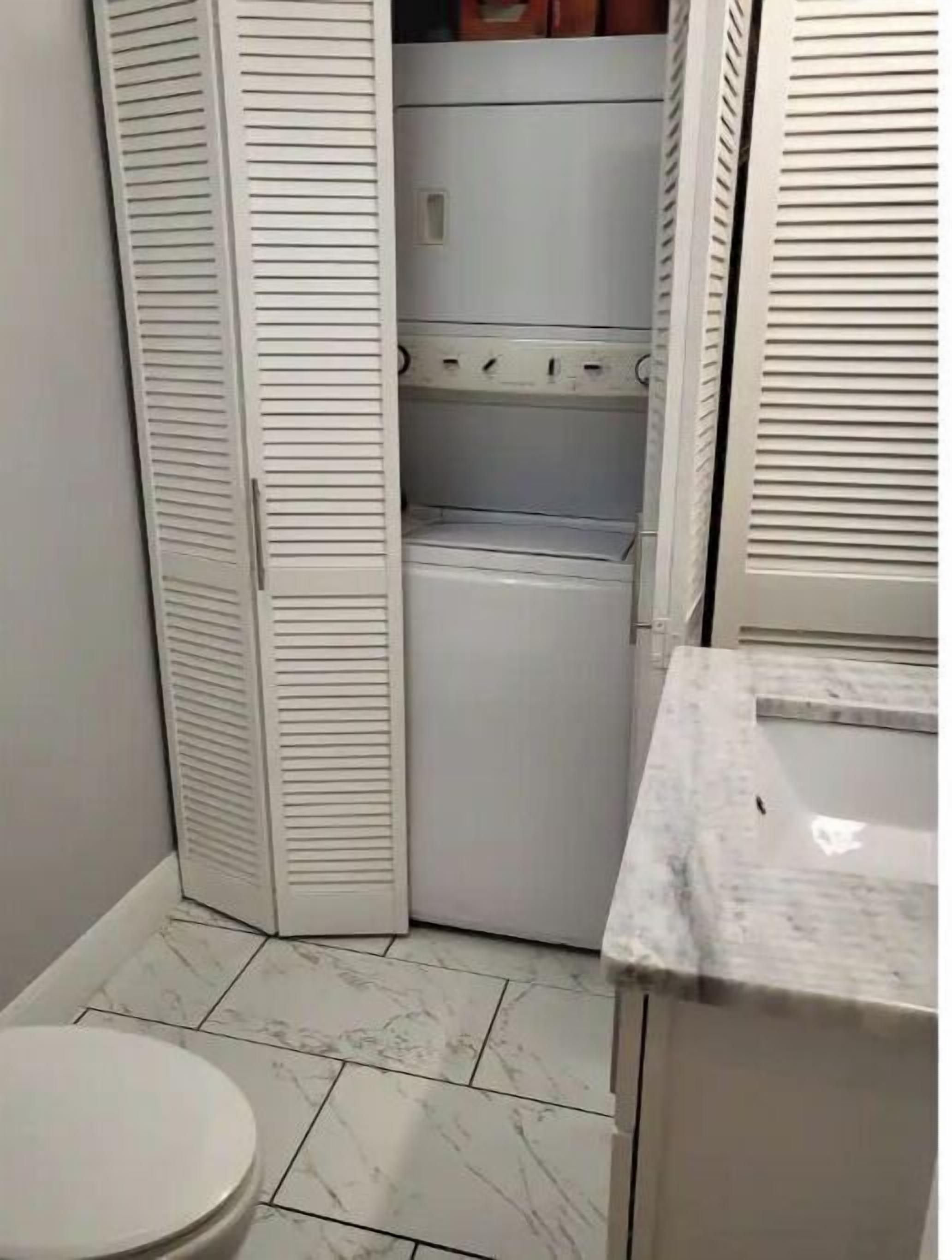 Une petite salle de bain comprenant des toilettes, un lave-linge et un lavabo.