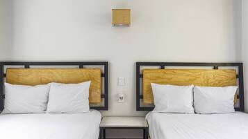 Ein Hotelzimmer mit zwei Betten, jeweils mit weißer Bettwäsche und hölzernen Kopfteilen.