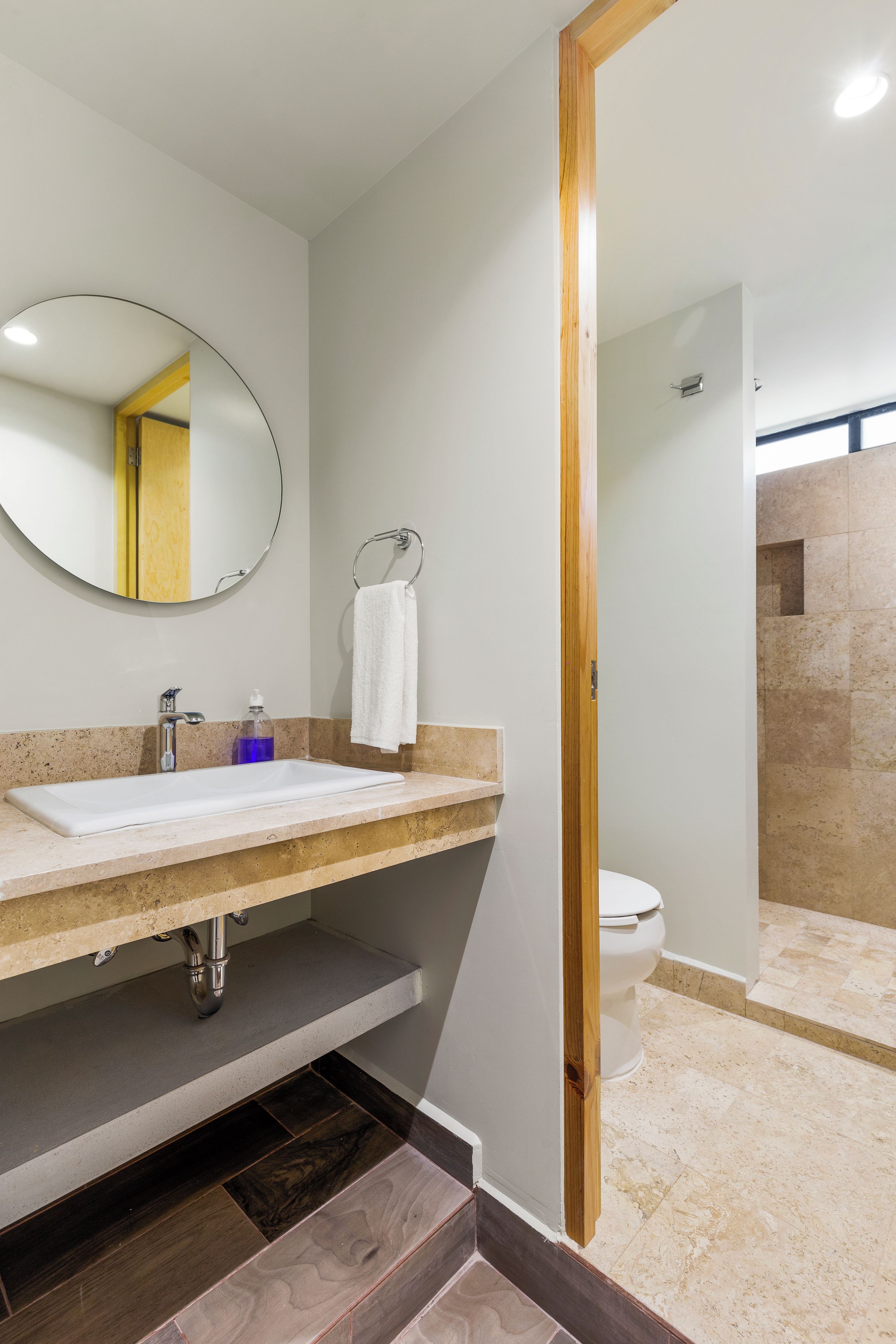A modern bathroom with a sink, mirror, and towel rack.