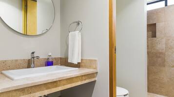 A modern bathroom with a sink, mirror, and towel rack.