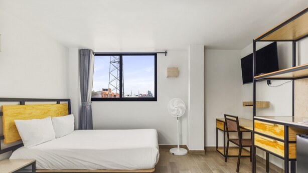 A hotel room with two beds, a desk, a chair, a TV, and a window with a view of buildings. - Lago Zirahuén By HomiRent (Mexico City)