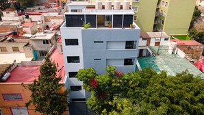 A multi-story building with balconies, a rooftop garden, and a green sports field. - Lago Zirahuén By HomiRent (Mexico City)