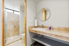 Une salle de bain équipée d’une douche, de toilettes, d’un lavabo et d’un miroir.