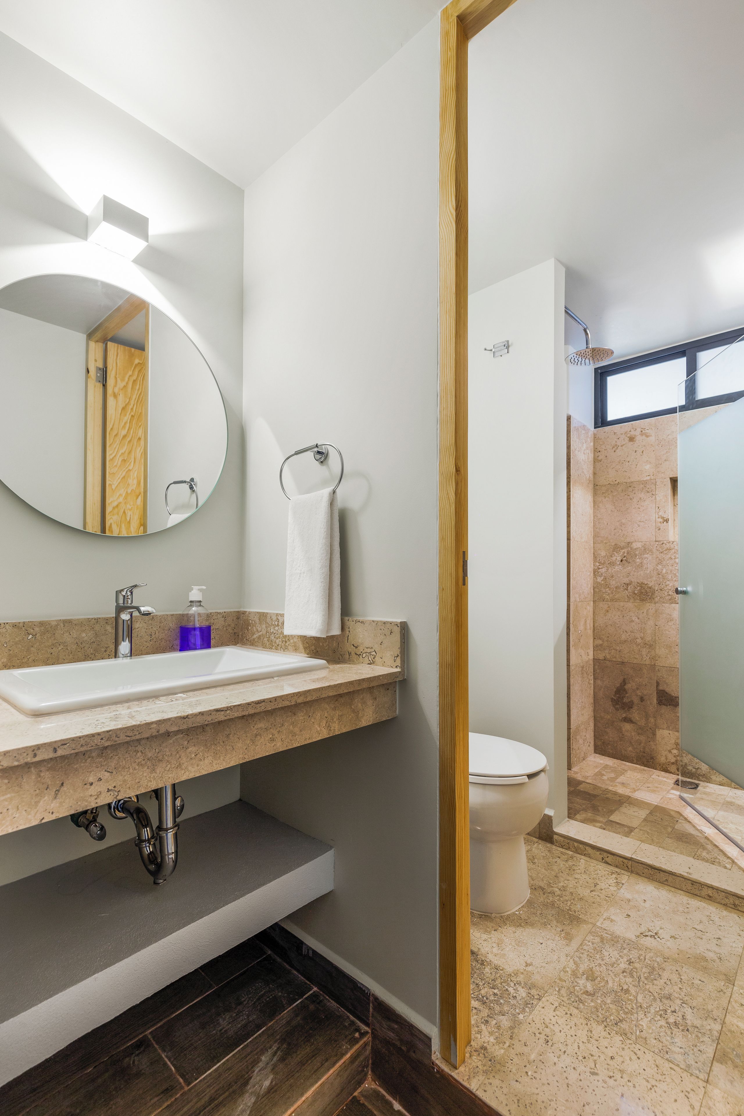 Un baño moderno con lavamanos, espejo y retrete.