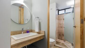 A modern bathroom with a large sink, mirror, and shower.