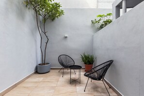 Un petit espace extérieur aménagé avec deux chaises et une plante en pot.