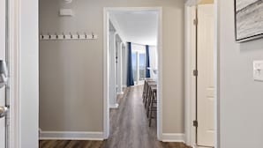 A hallway with a wooden floor, a coat rack, and a door leading to a balcony with a view. - "Siren's Song" Oceanfront Beach House w/pool (Murrells Inlet)