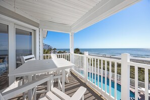 A covered outdoor area with a pool, white furniture, and a view of the ocean. - Oceanfront Home, Pool Steps Away, Dogs OK (Murrells Inlet)