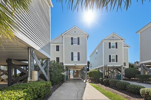 A row of two-story buildings with a central walkway, supported by wooden stilts, under a clear sky. - Oceanfront Home, Pool Steps Away, Dogs OK (Murrells Inlet)