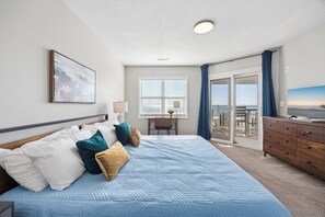 A hotel room with a bed, a desk, a chair, a dresser, a window with blinds, a view of the sea, and a ceiling light. - Oceanfront Home, Pool Steps Away, Dogs OK (Murrells Inlet)
