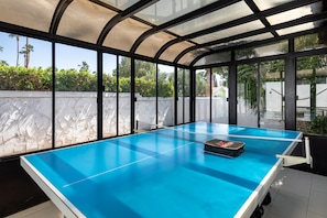 Enjoy a game of tennis in a spacious room with a lush view.