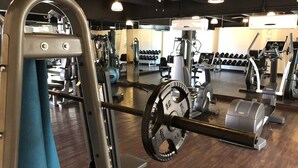 A gym with various exercise equipment, including a squat rack, dumbbells, and cardio machines. - Condominios 180PR (Puerto Vallarta)