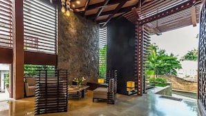 A spacious lobby with a stone wall, modern furniture, and a view of greenery outside. - Condominios 180PR (Puerto Vallarta)