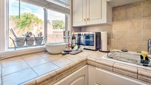 A kitchen with a large window, a microwave, a sink, and a dish rack with utensils. - 1 Mi to Dtwn Burbank: Mod Gem w/ Private Yard (Burbank)
