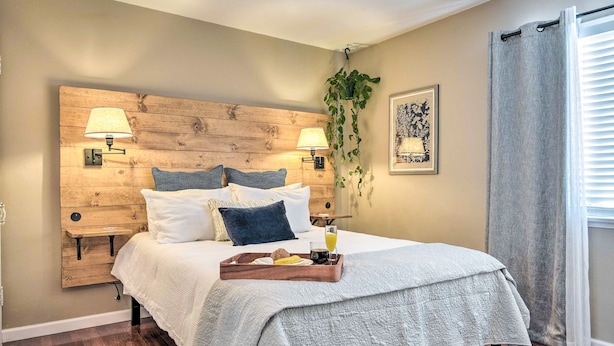 A neatly made bed with a wooden headboard, two bedside lamps, a tray with breakfast items, and a hanging plant. - 1 Mi to Dtwn Burbank: Mod Gem w/ Private Yard (Burbank)