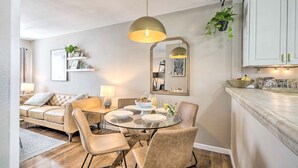 A modern dining area with a round glass table, beige upholstered chairs, and a pendant light. A white cabinet with a mirror above the table is visible. - 1 Mi to Dtwn Burbank: Mod Gem w/ Private Yard (Burbank)