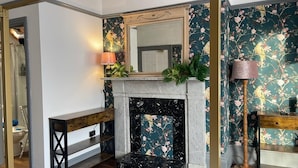 A room with a fireplace, a mirror, and floral wallpaper.