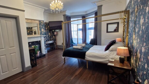 A hotel room with a large bed, a TV, a fireplace, and a view of the city.