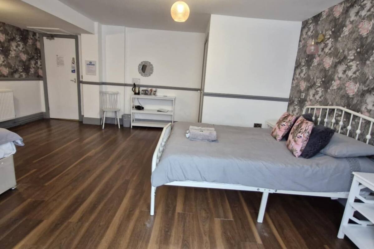A bedroom with two beds, a desk, and a radiator.