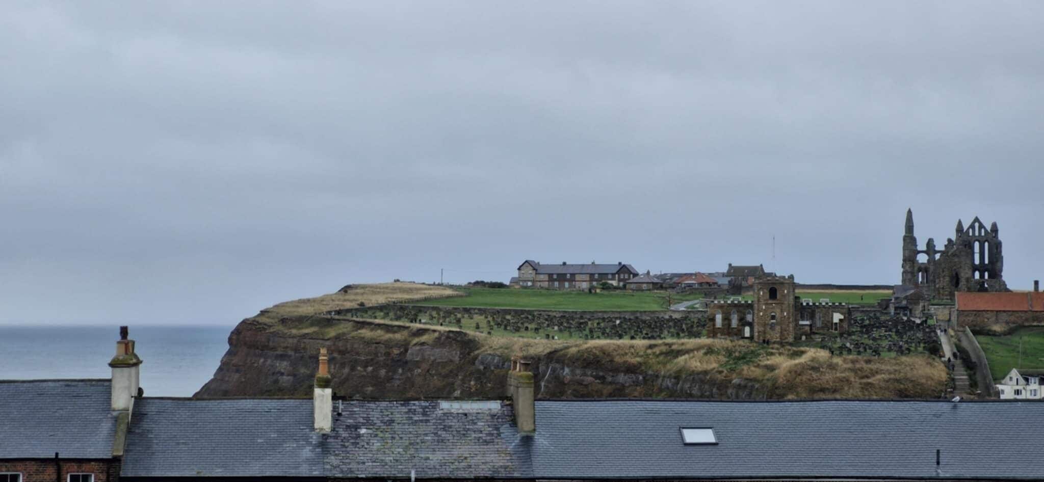A coastal town with a prominent castle and church on a hill, overlooking the sea.