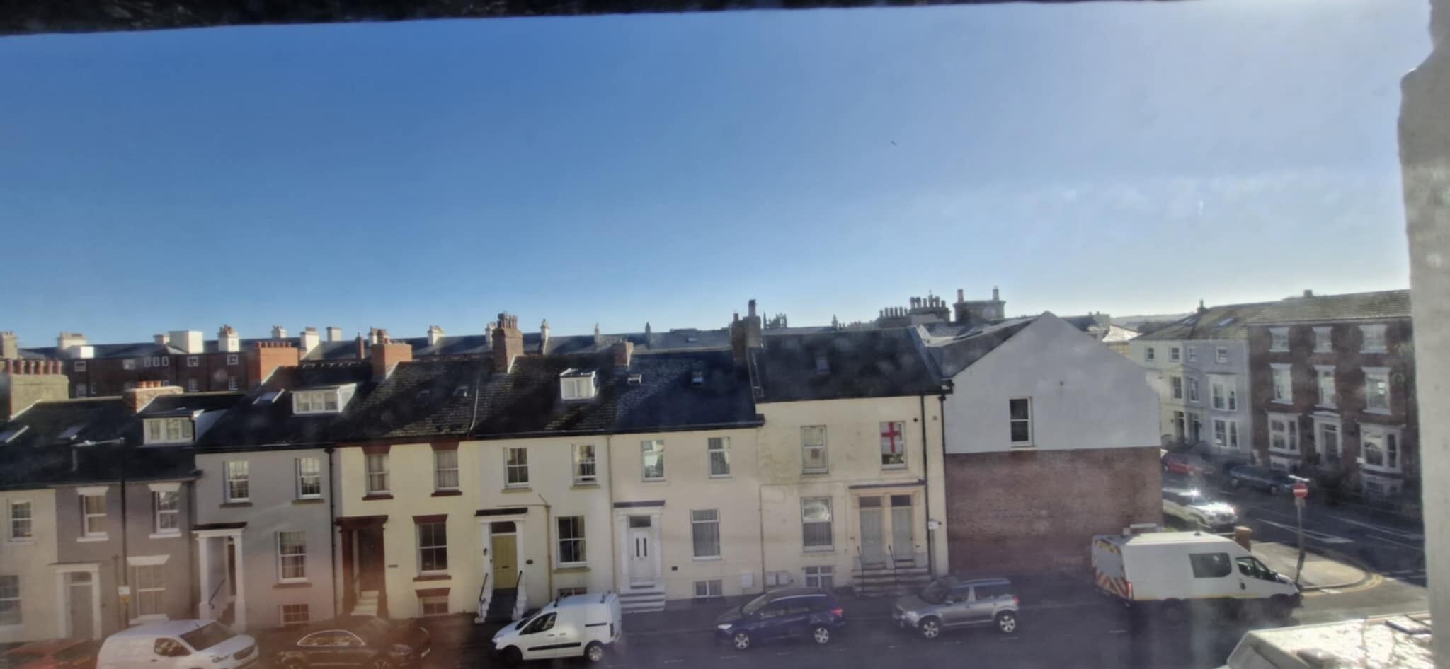 Une rangée de maisons mitoyennes avec un fourgon blanc garé devant.