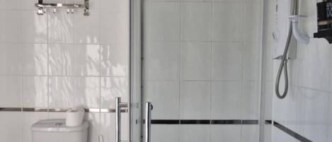 Une salle de bain avec une douche à parois de verre, des toilettes et un porte-serviettes.