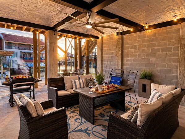 Un patio al aire libre con mobiliario de mimbre, una parrilla y vistas a edificios al fondo.