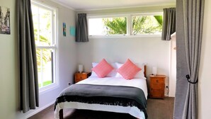 A bedroom with a bed, two bedside tables, and a window with curtains.