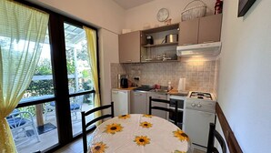 Una cucina compatta con un tavolo da pranzo ricoperto da una tovaglia con girasoli, un fornello e un lavello.