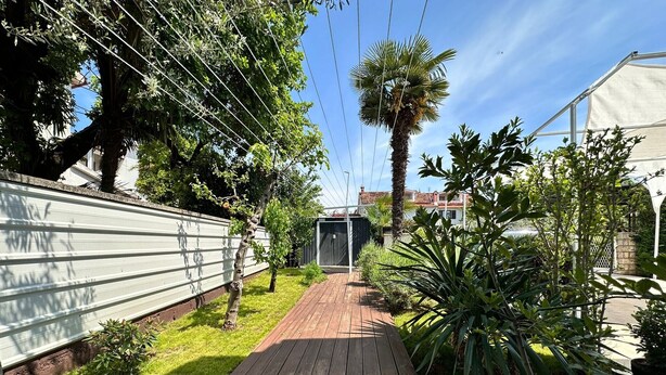 A wooden deck leading to a covered area, surrounded by lush greenery and a metal fence. - Apartments Cocolo - Superior One Bedroom Apartment with Terrace (Porec)