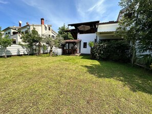 A spacious backyard with a well-maintained lawn, a barbecue area, and a small garden.