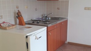 A compact kitchen with a white refrigerator, wooden cabinets, a stainless steel sink, and a tiled backsplash. - Apartments Semafor - One Bedroom Apartment with Terrace A1 (Seget Vranjica)