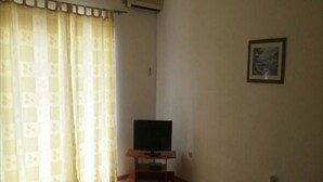 A living room with a television on a wooden stand, a sofa, and a small table. - Apartments Semafor - One Bedroom Apartment with Terrace A1 (Seget Vranjica)