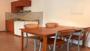 Une cuisine compacte comprenant une table et des chaises, un four encastré et un petit plan de travail.