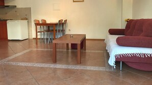 Un espace de vie compact comprenant un coin repas, un canapé et une kitchenette.