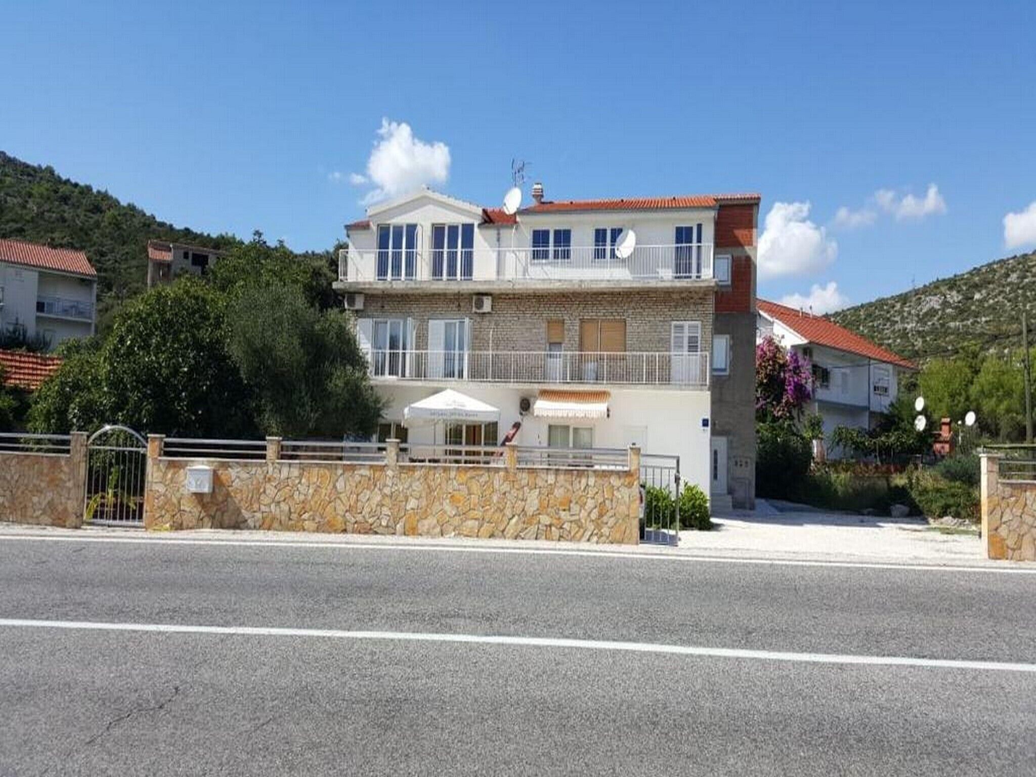 Ein zweistöckiges Gebäude mit einer Steinaußenfassade, einem Balkon und einer kleinen Außenbereich-Sitzgelegenheit.