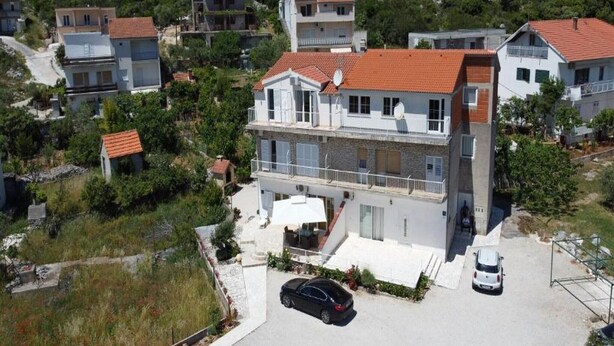 A multi-story residential building with a red-tiled roof, a balcony, and a car parked in front. - Apartments Semafor - One Bedroom Apartment with Terrace and Sea View A3 (Seget Vranjica)
