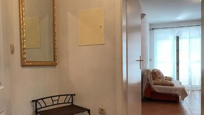 A hallway with a metal bench, a mirror, and a door leading to a bedroom with a bed and curtains. - Apartments Semafor - One Bedroom Apartment with Terrace and Sea View A4 (Seget Vranjica)