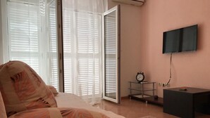 A bedroom with a bed, a TV mounted on the wall, and a sliding glass door leading to a balcony. - Apartments Semafor - One Bedroom Apartment with Terrace and Sea View A4 (Seget Vranjica)