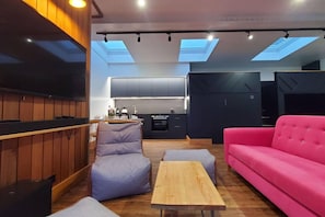 A modern living room with a flat-screen TV, a pink sofa, and a wooden coffee table.