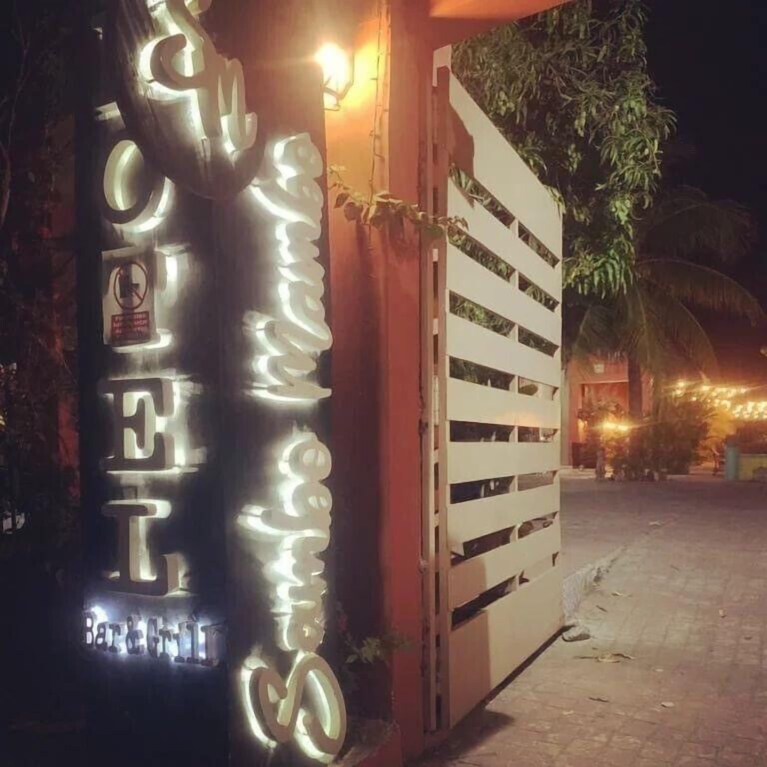 A building with a sign that reads "Bar & Grill" and a gated entrance.