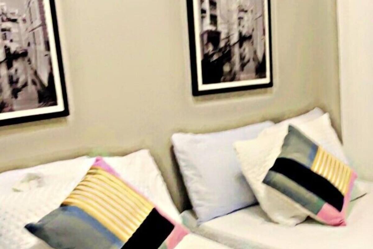 A hotel room with two beds, each with a pillow and a framed picture on the wall.