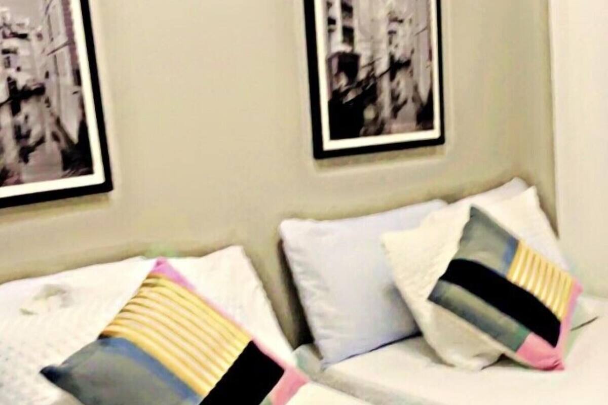 A hotel room with two beds, each with a pillow and a framed picture on the wall.