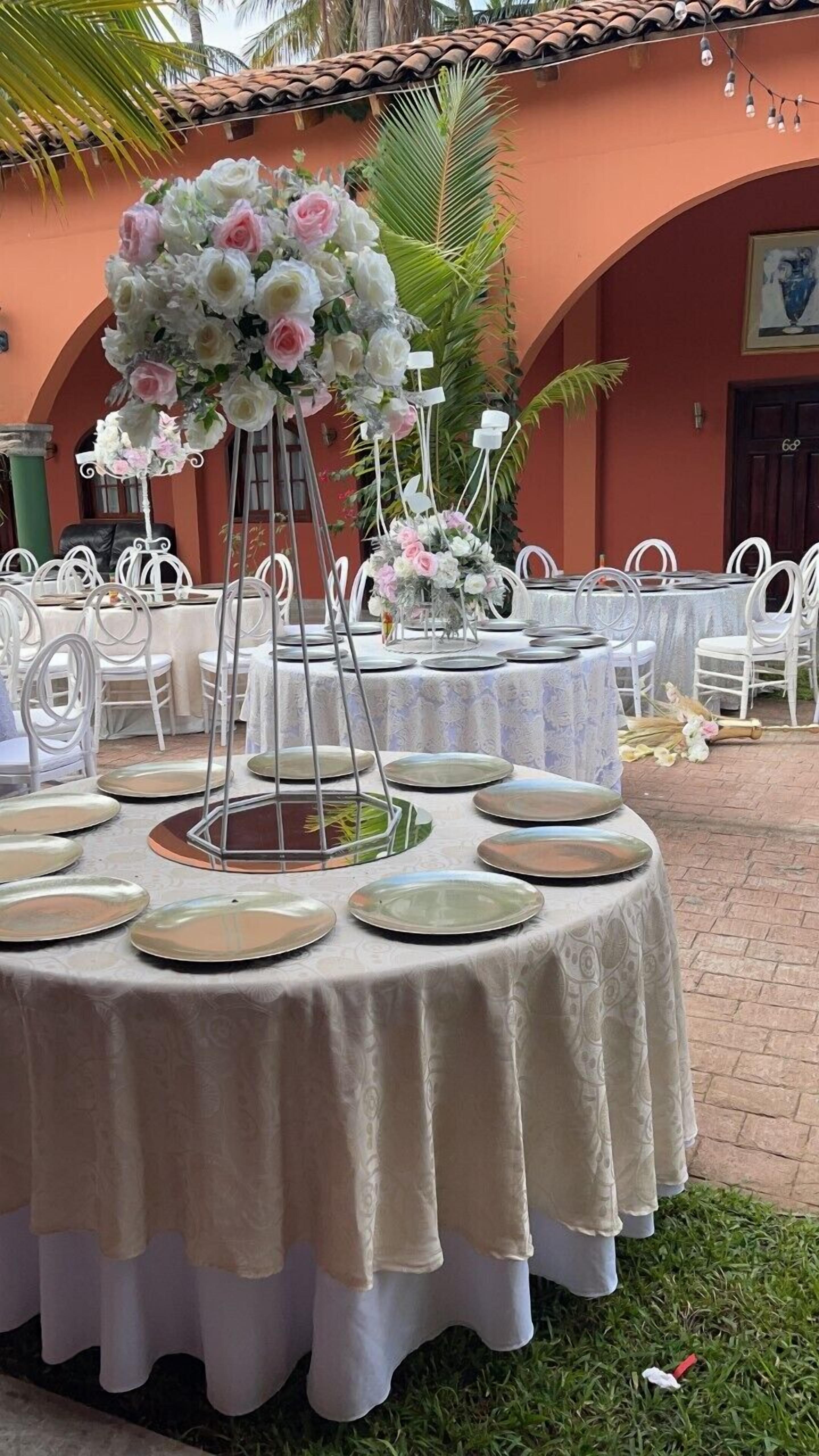 A table set for a formal event with white chairs and a floral centerpiece.