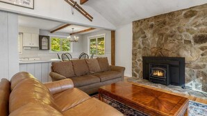 A cozy living room with a stone fireplace, leather sofas, and a wooden coffee table. - Spacious Stratton Mountain Home  - Perfect for families! (Winhall)