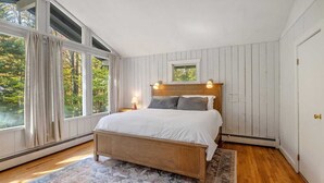 A bedroom with a wooden bed, a large window, and a view of trees. - Spacious Stratton Mountain Home  - Perfect for families! (Winhall)