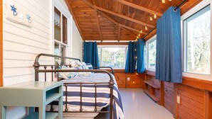 Un dormitorio acogedor con techo de madera, estructura de cama de metal, mesita de noche y un ventanal con cortinas.