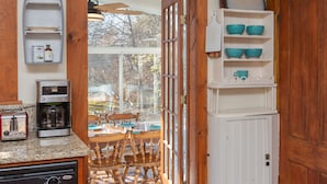 Una cocina con cafetera, tostadora y sillas de madera.